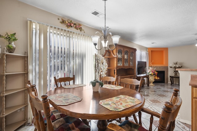 dining area with a fireplace, a chandelier, and a textured ceiling