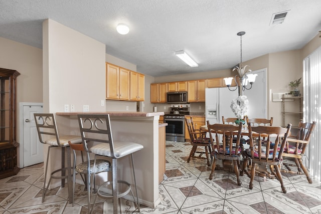 kitchen featuring kitchen peninsula, a chandelier, stainless steel range, white fridge with ice dispenser, and a breakfast bar