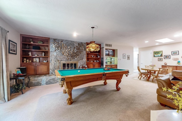 playroom with a skylight, pool table, a fireplace, light carpet, and built in shelves