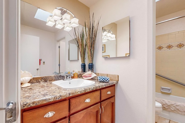 bathroom featuring a tile shower, a skylight, toilet, tile patterned floors, and vanity