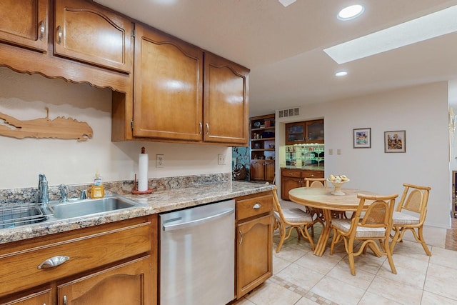 kitchen with sink, light tile patterned floors, a skylight, and dishwasher