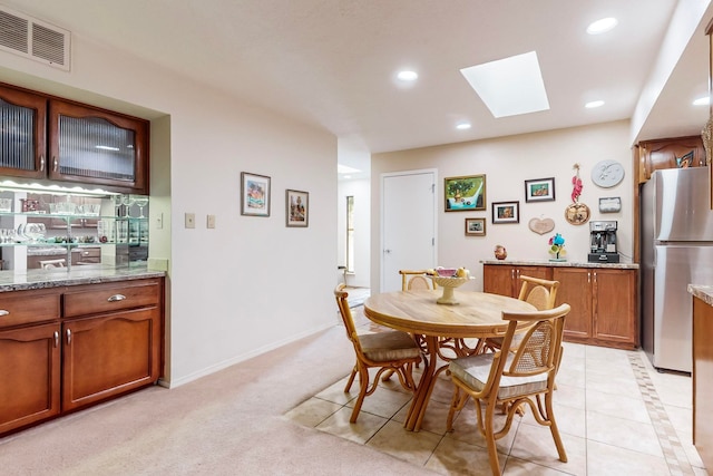 dining area featuring light carpet and a skylight