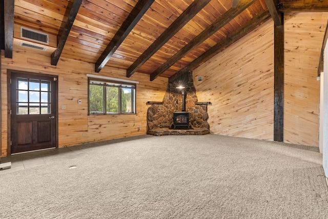 unfurnished living room featuring a wood stove, vaulted ceiling with beams, and light carpet