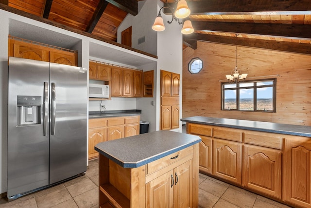 kitchen featuring a center island, wooden walls, light tile patterned floors, stainless steel fridge with ice dispenser, and beam ceiling