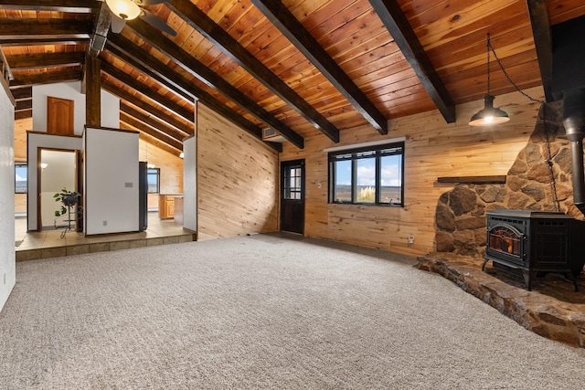 unfurnished living room featuring wood walls, a wood stove, and carpet flooring