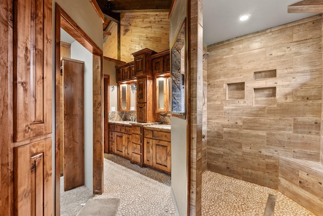 bathroom with walk in shower, vanity, and wooden walls