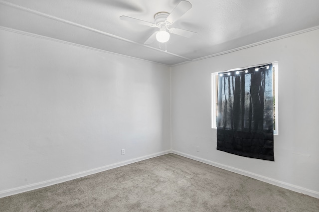 spare room with ceiling fan, crown molding, and light colored carpet