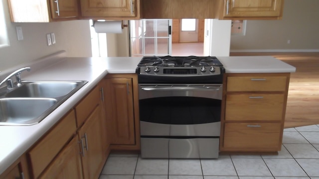 kitchen with kitchen peninsula, stove, sink, and light tile patterned floors