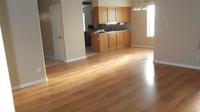 kitchen featuring light wood-type flooring, light brown cabinets, and a notable chandelier