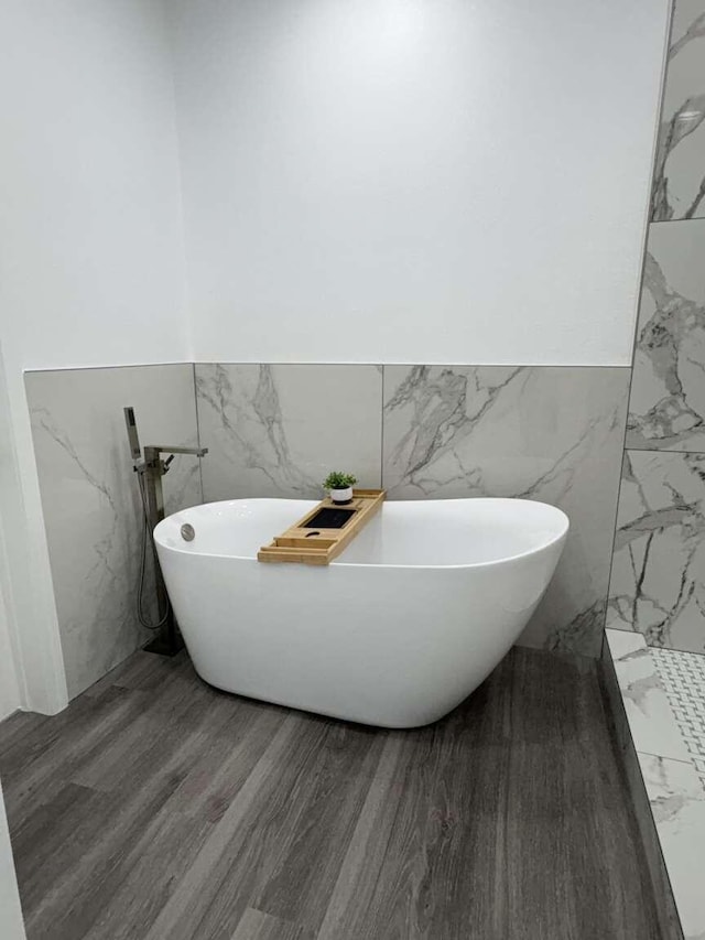 bathroom featuring hardwood / wood-style flooring, a bath, and tile walls