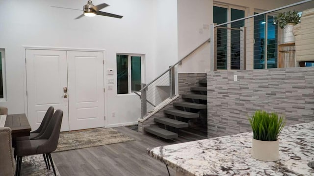 foyer entrance featuring hardwood / wood-style floors, ceiling fan, tile walls, and a high ceiling