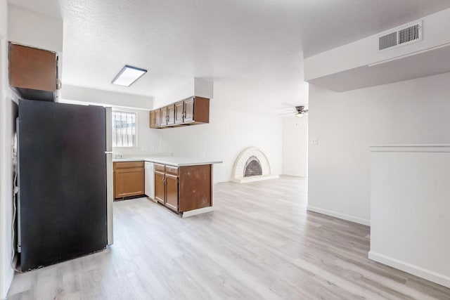 kitchen with kitchen peninsula, light wood-type flooring, white dishwasher, ceiling fan, and stainless steel refrigerator