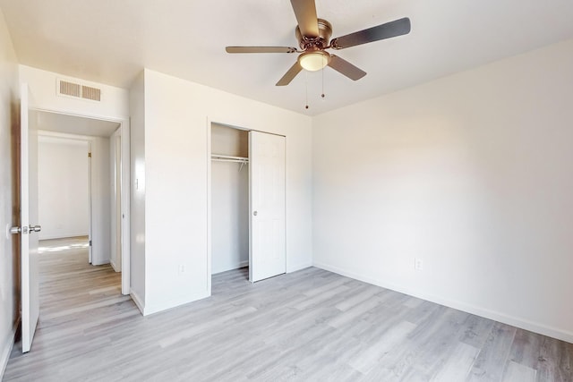 unfurnished bedroom with ceiling fan, light wood-type flooring, and a closet