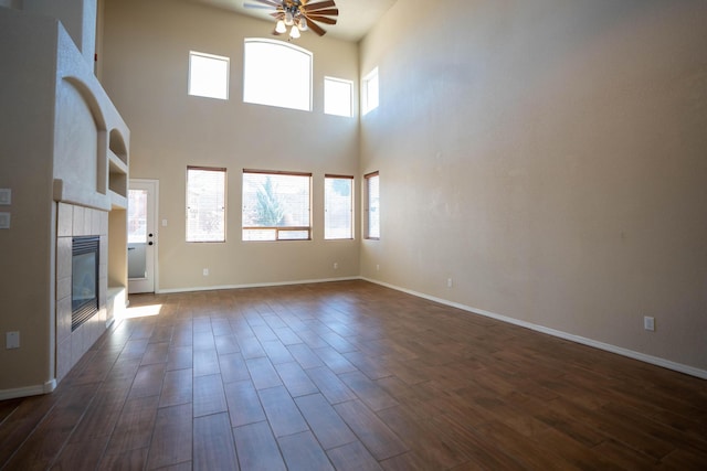 unfurnished living room with dark wood-type flooring, a healthy amount of sunlight, and a high ceiling