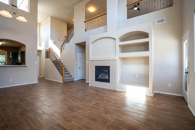 unfurnished living room featuring a healthy amount of sunlight, a high ceiling, and dark hardwood / wood-style flooring