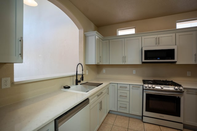 kitchen featuring light tile patterned floors, stainless steel appliances, sink, and a wealth of natural light