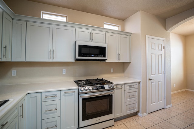 kitchen with stainless steel appliances, a textured ceiling, and light tile patterned floors