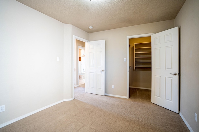 unfurnished bedroom featuring a walk in closet, a closet, and light colored carpet