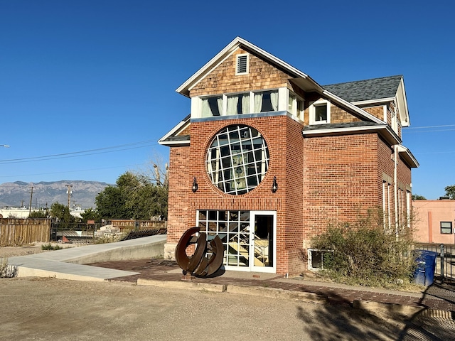 view of front of home featuring brick siding, fence, and a mountain view