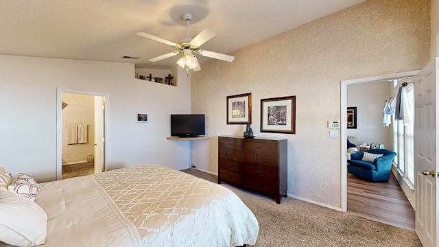 carpeted bedroom featuring ceiling fan, vaulted ceiling, and ensuite bath