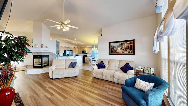 living room featuring lofted ceiling, a tiled fireplace, light hardwood / wood-style floors, and ceiling fan