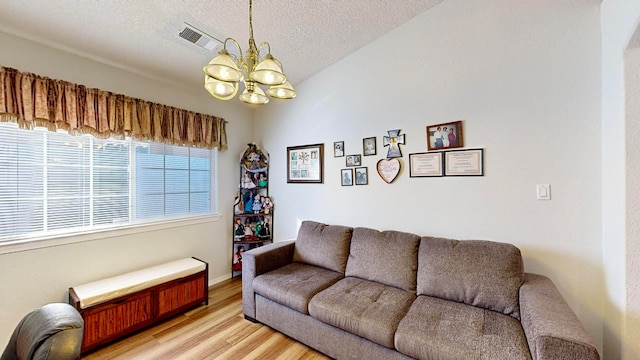 living room featuring an inviting chandelier, a textured ceiling, and light wood-type flooring