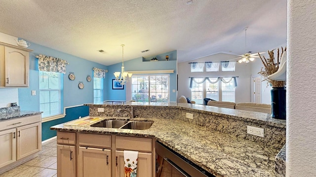 kitchen featuring lofted ceiling, a textured ceiling, light brown cabinetry, ceiling fan with notable chandelier, and sink