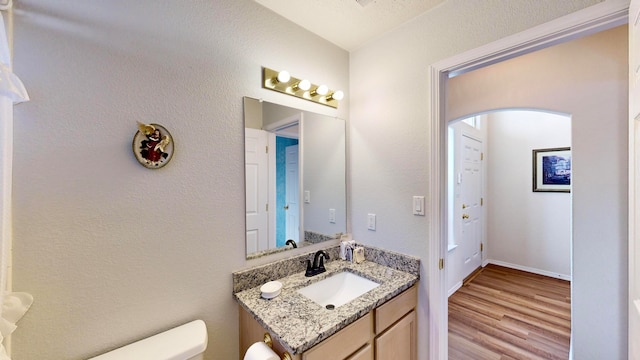 bathroom featuring toilet, hardwood / wood-style flooring, and vanity