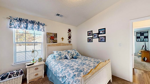 carpeted bedroom featuring a textured ceiling and vaulted ceiling