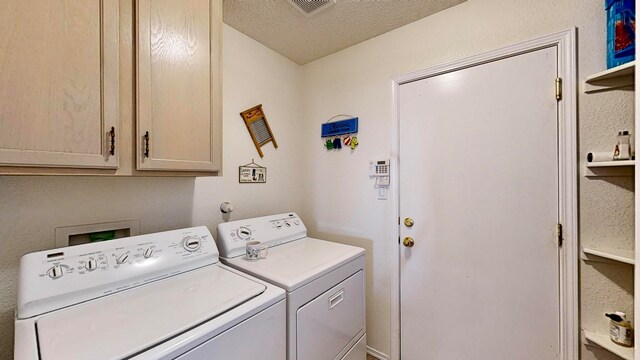 clothes washing area with cabinets, a textured ceiling, and washer and dryer