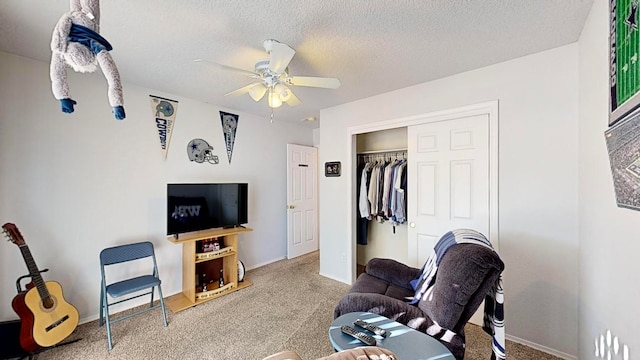 living room with ceiling fan, carpet flooring, and a textured ceiling