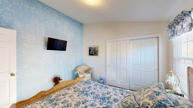 bedroom with lofted ceiling, a textured ceiling, and a closet