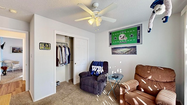 living area with a textured ceiling, light hardwood / wood-style floors, and ceiling fan