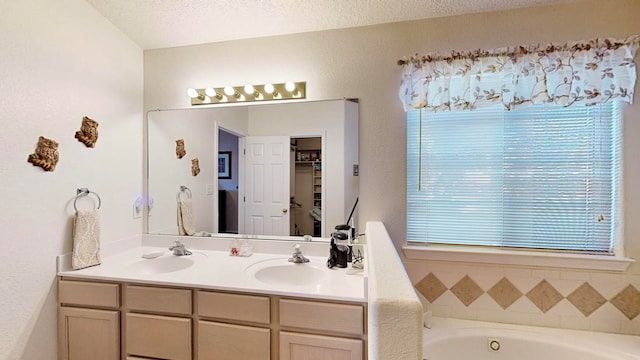 bathroom with vanity, a textured ceiling, and a bath