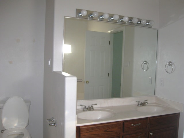 full bath with a sink, toilet, and double vanity