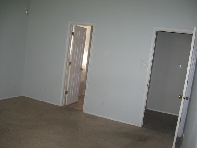 spare room featuring light colored carpet and baseboards