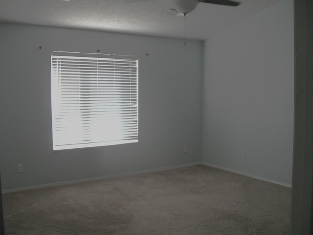 carpeted empty room featuring ceiling fan, a textured ceiling, and baseboards