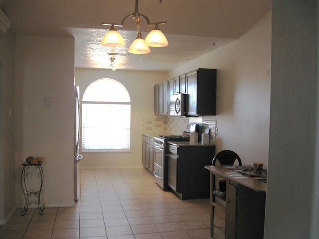 kitchen with light countertops, hanging light fixtures, backsplash, appliances with stainless steel finishes, and a textured ceiling