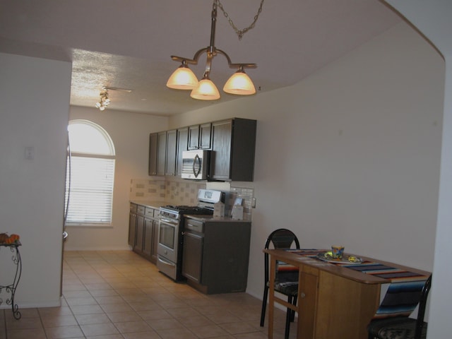 kitchen featuring a textured ceiling, light tile patterned floors, stainless steel appliances, light countertops, and tasteful backsplash