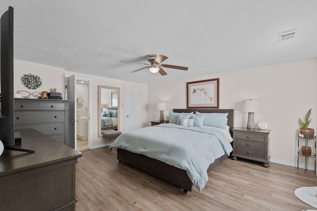 bedroom with a textured ceiling, ceiling fan, visible vents, baseboards, and light wood finished floors