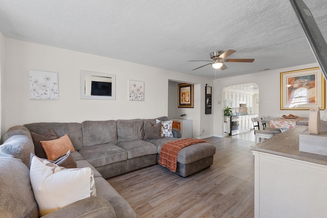 living area with arched walkways, visible vents, ceiling fan, a textured ceiling, and wood finished floors