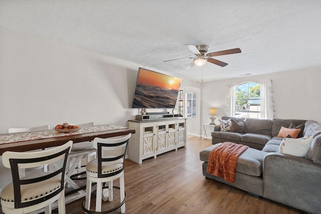 living area featuring a textured ceiling, a ceiling fan, and wood finished floors