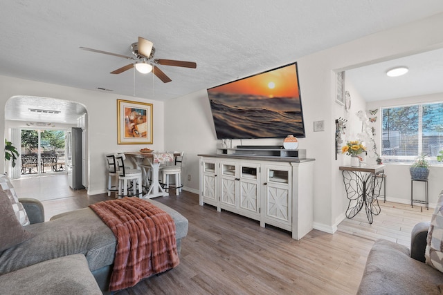 living room with ceiling fan, light hardwood / wood-style floors, and a textured ceiling