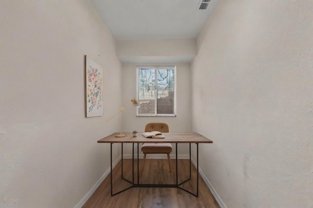 office space with baseboards, visible vents, and wood finished floors