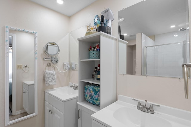 bathroom featuring a stall shower, two vanities, a sink, and recessed lighting