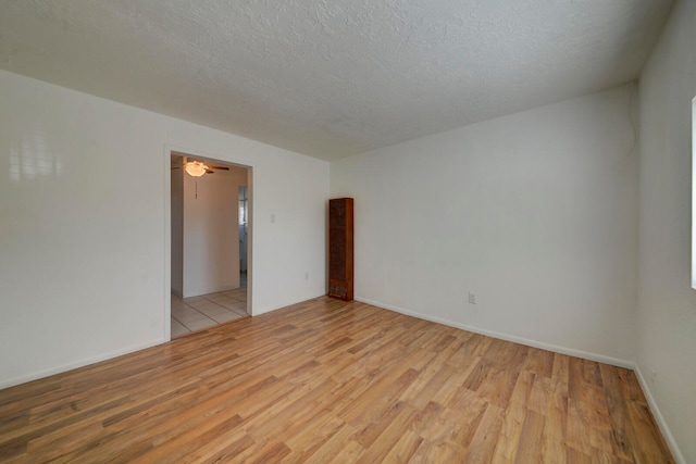 empty room featuring a textured ceiling, light hardwood / wood-style floors, and ceiling fan