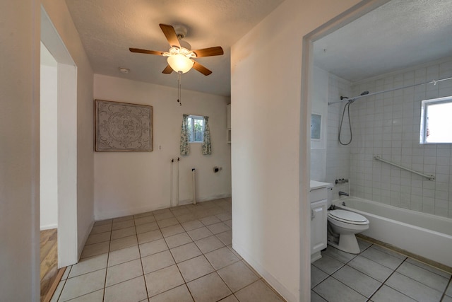 full bathroom featuring toilet, tile patterned flooring, tiled shower / bath, vanity, and a textured ceiling