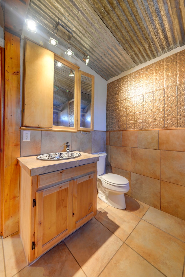 bathroom featuring vanity, toilet, tile walls, and tile patterned flooring