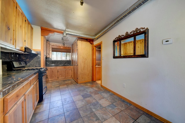 kitchen with sink, gas stove, a textured ceiling, and tasteful backsplash