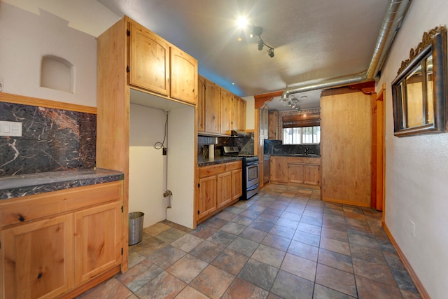 kitchen featuring rail lighting, backsplash, sink, and stainless steel gas range oven